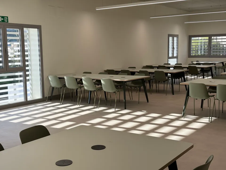 Sala de coworking con mesas colectivas, tomas de corriente integradas y luz natural