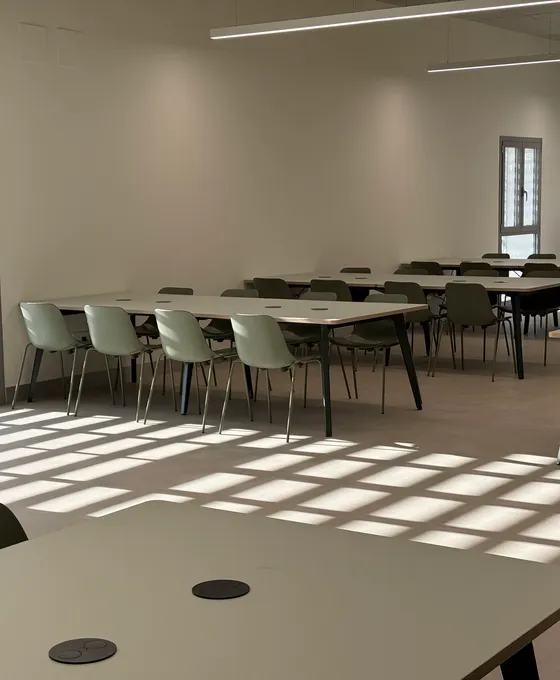Sala de coworking con mesas colectivas y tomas de corriente integradas, equipada por eqpro