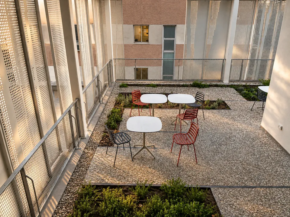 Terraza exterior con mesas redondas y sillas metálicas rojas y negras