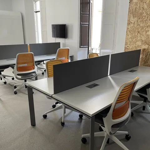 Puestos de trabajo con mamparas grises y sillas en tono mostaza