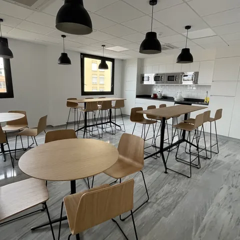 Office de personal con cocina equipada y mesas redondas