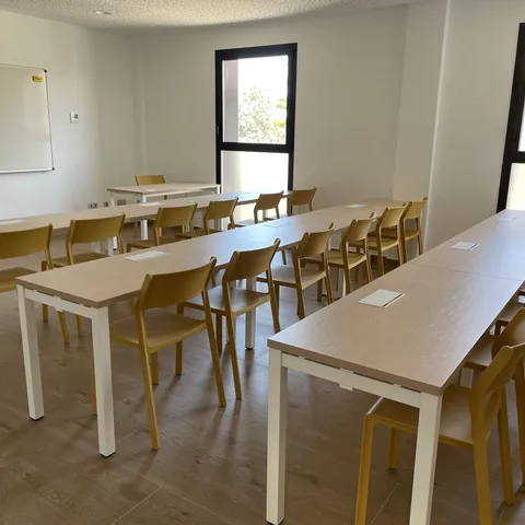 Aula con mesas colectivas y sillas apilables