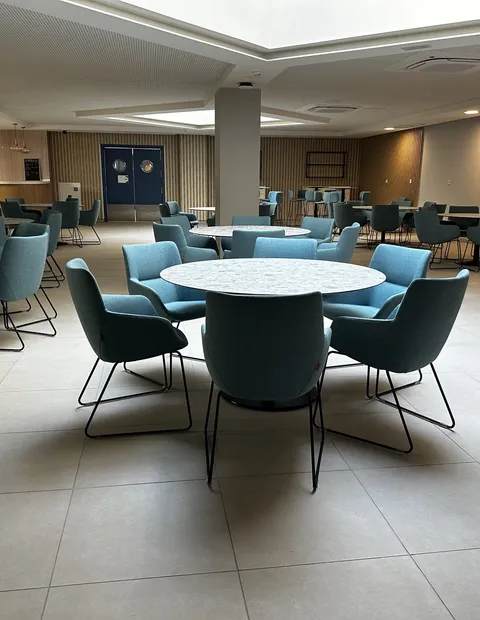 Comedor de personal con mesas redondas y sillas en verde azulado