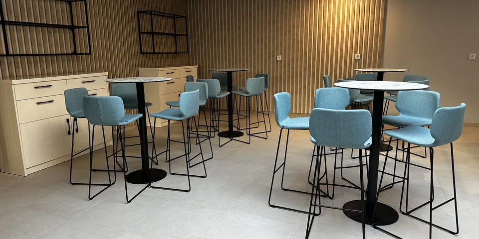 Zona informal de cafetería con mesas altas de madera