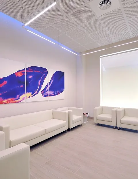Sala de espera clínica con sofás blancos y obra de arte
